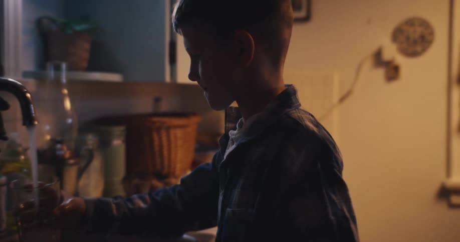 Boy getting water from the sink tap