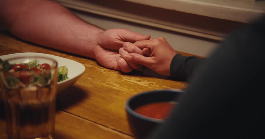 Two people holding hands while saying grace