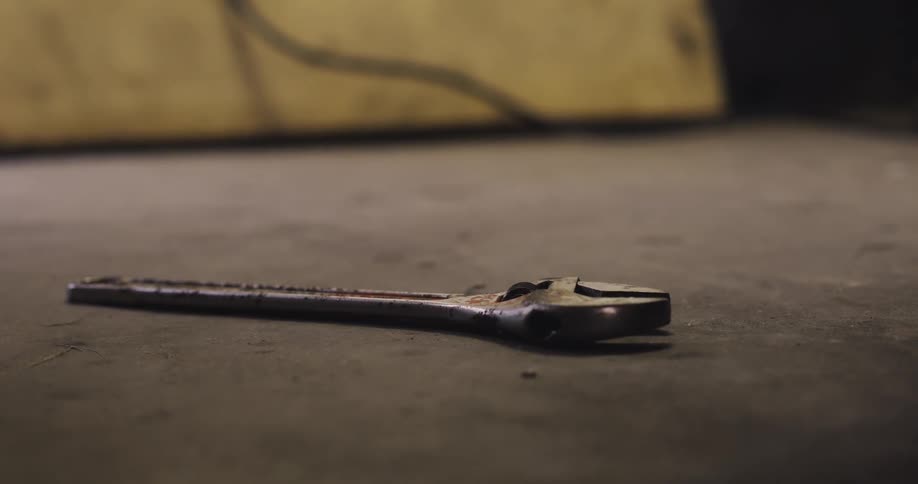 A person picking up a wrench off a floor