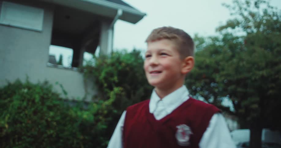 A smiling boy in a school uniform catches and plays with a soccer ball