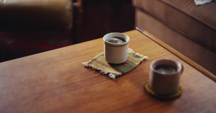 Coffee table with two mugs on coasters in cozy setting