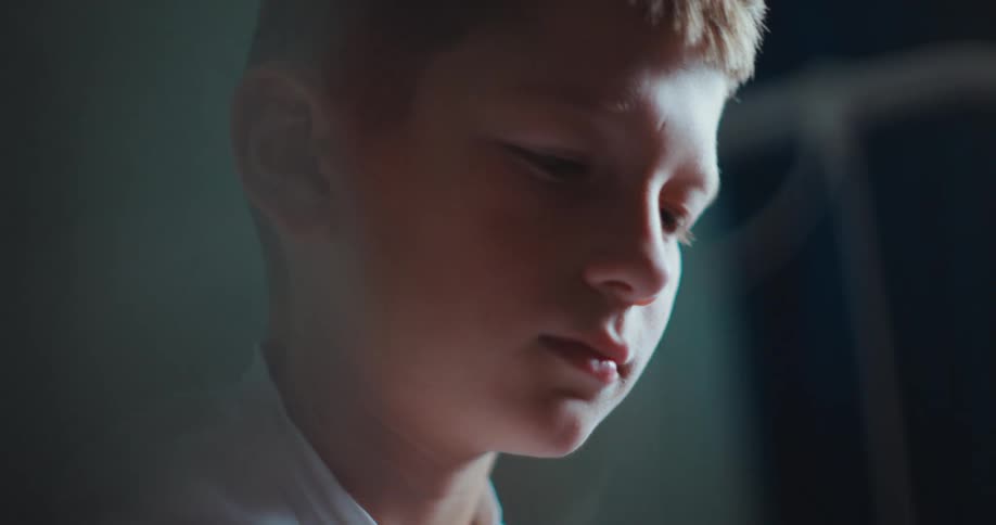 Young boy wearing a white dress shirt indoors with a contemplative facial expression during day time
