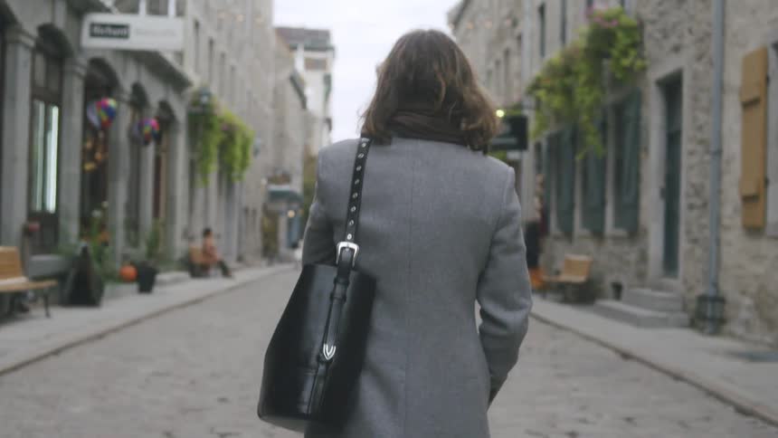Woman walks on a neighborhood street with her purse over her shoulder