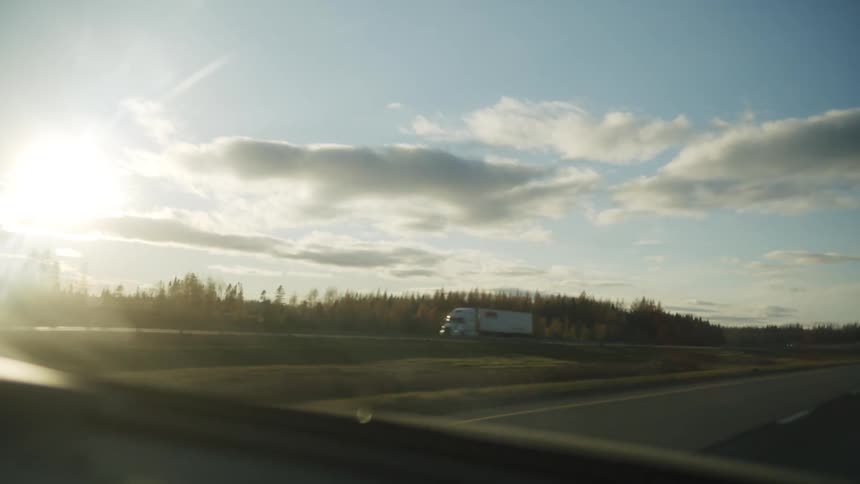 A car on the road at sunset moving under an overpass