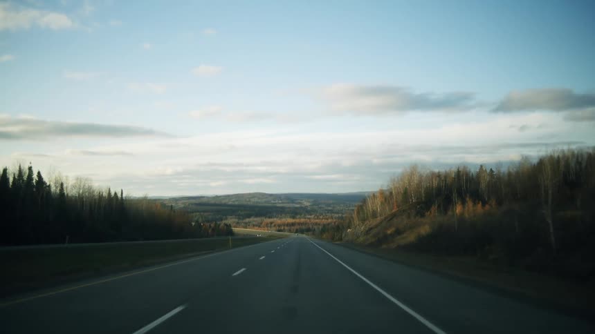 Paved highway surrounded by vegetation and mountains in the background