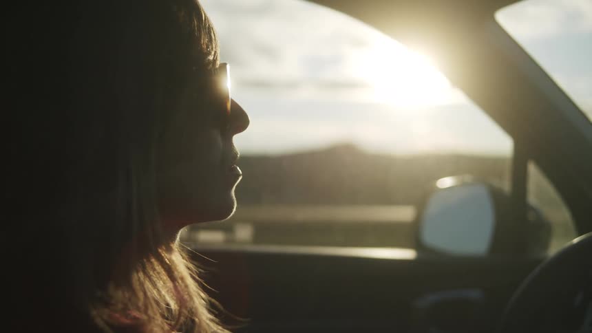 Young woman wearing sunglasses as she drives an automobile