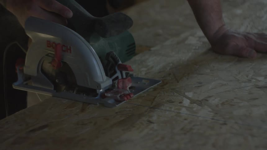 Electric circular saw cuts a wooden panel during a construction task