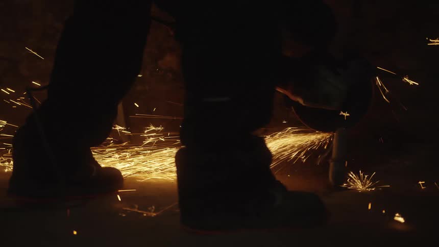 Person operating a machine and sparks flying
