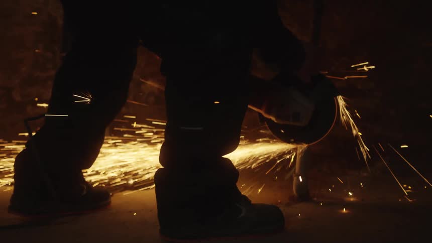 Sparks scatter as a power tool cuts metal in an industrial setting