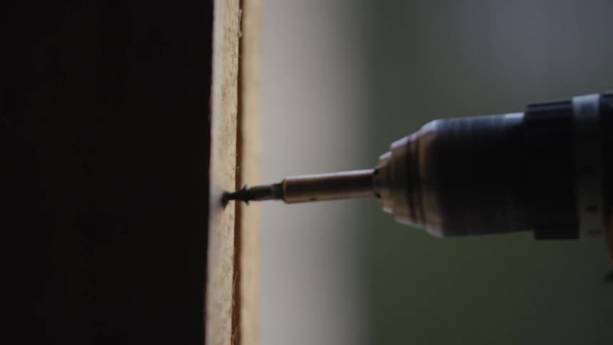 The construction worker drills a screw into the wood