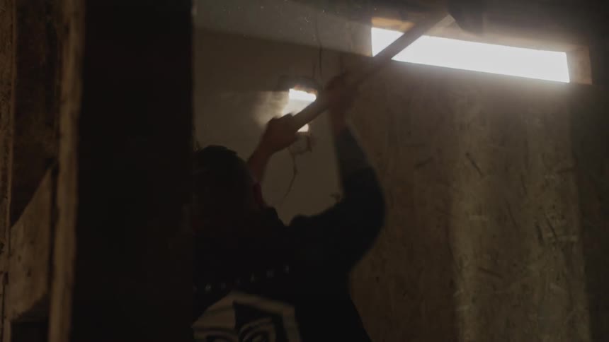 Man with a sledgehammer breaking through a concrete wall