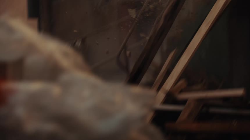 The video shows a dilapidated building where dust and debris are being shaken or blown through the gaps in the stone walls in the foreground there are rusted metal railings and wooden beams that appear to be part of a crumbling staircase or entryway