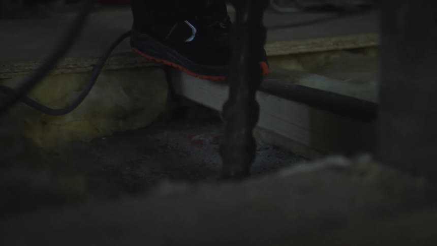 Safety shoe on wooden beam with insulation in background at construction site