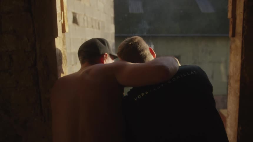 Two men are hugging and smoking