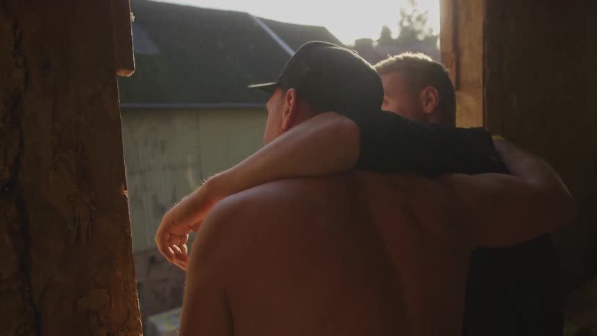 Two men embracing looking out the window