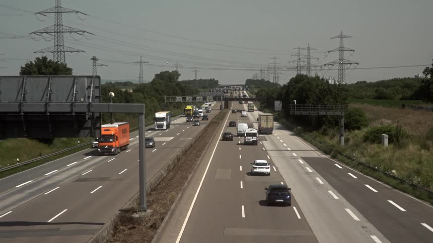 Trucks and cars move in traffic in both directions on the freeway