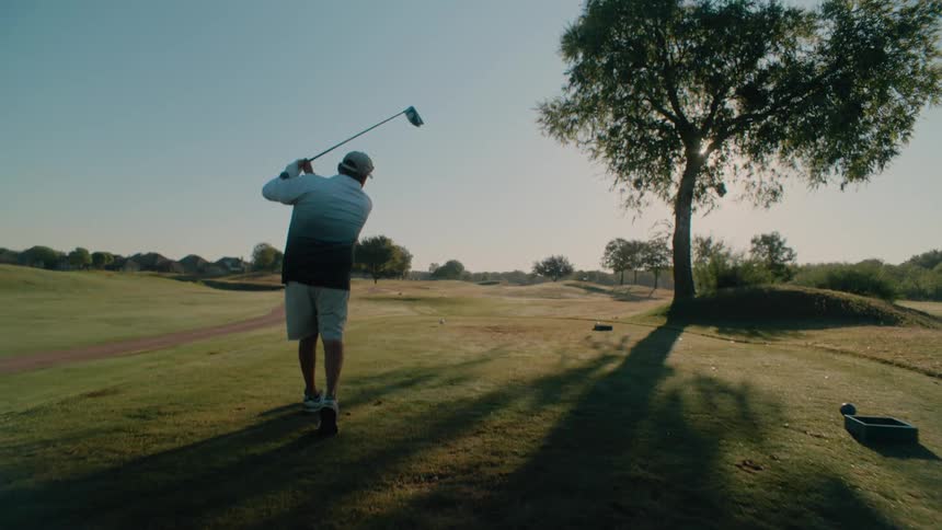 A man hitting a golf ball with a driver