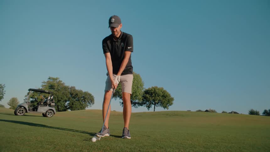 The man is preparing to drive the golf ball