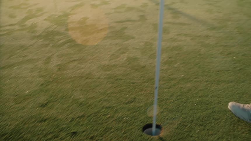 A man putting a ball into a cup while golfing
