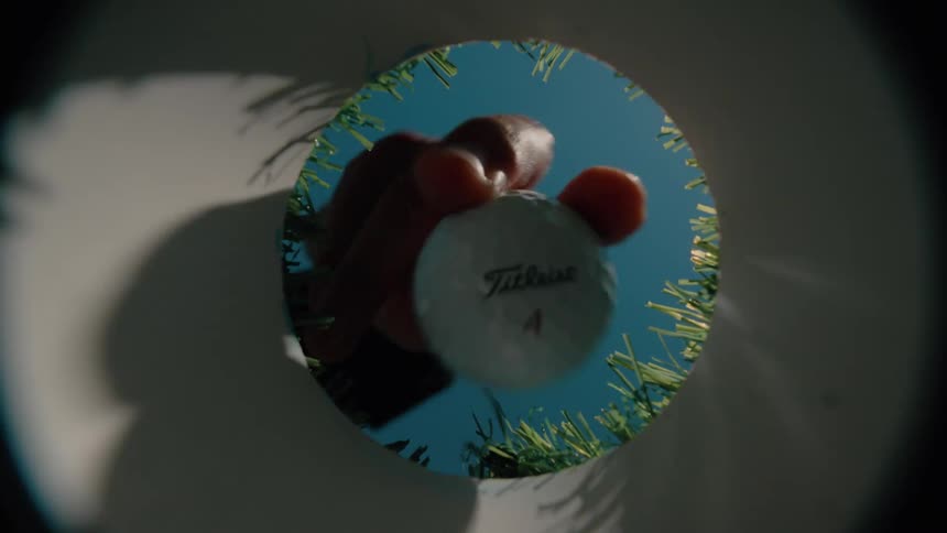 A man reaching into a golf cup to take out a ball