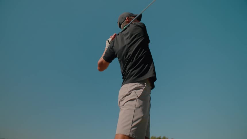 The man hits the golf ball with a wide swing