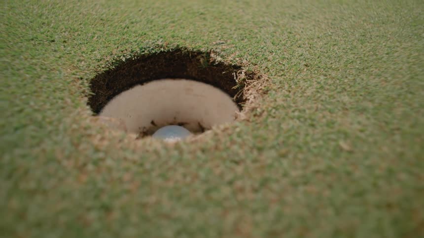 The golf ball falls in the hole and is quickly picked up
