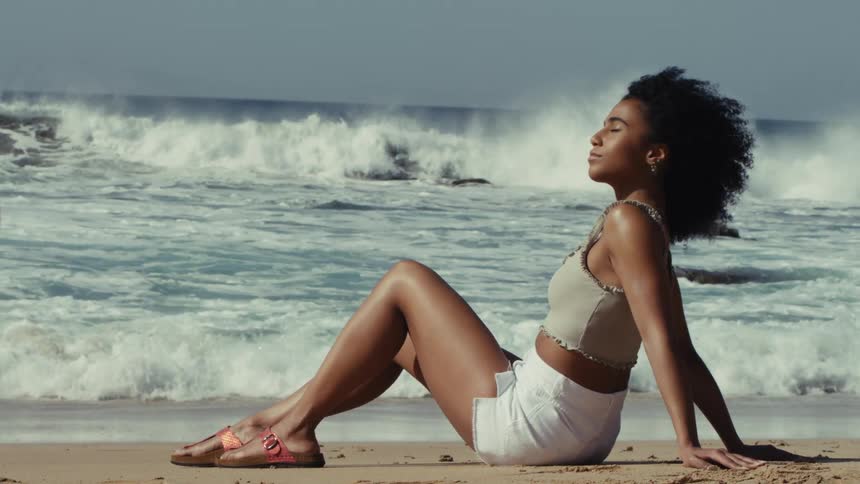 A young woman relaxes while sitting on a sunny beach