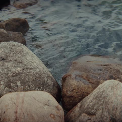 Rocks at the waters edge with gentle waves moving between the stones