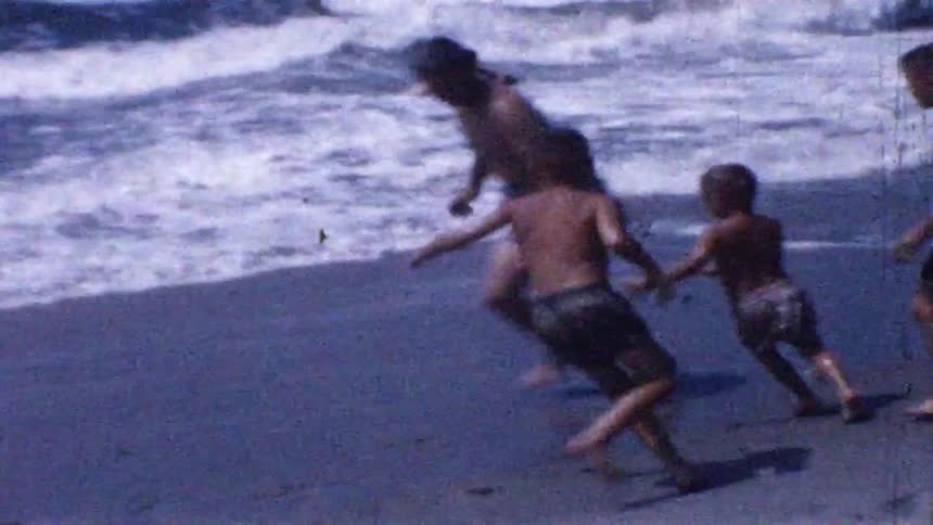 Children run across wet sand near ocean waves