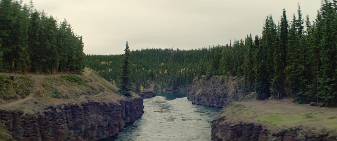 River flowing between rocky cliffs lined with conifer forest