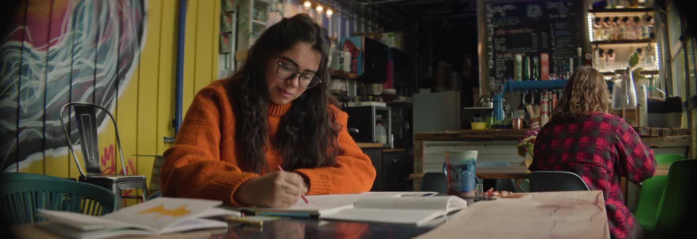 A woman is drawing in a cafe