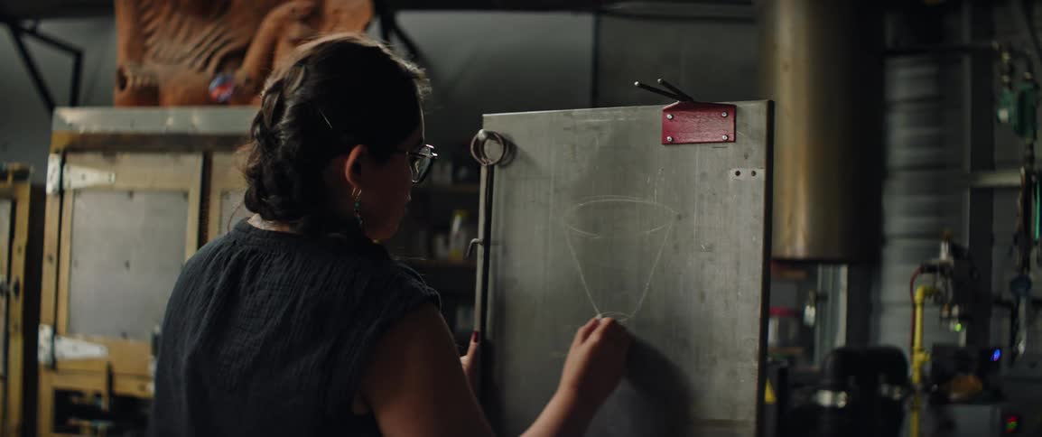 A woman plans her design on a chalk board in an industrial setting