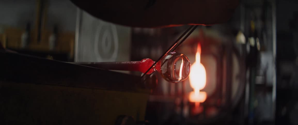 Molten glass bubble being shaped with a tool in a glassblowing workshop