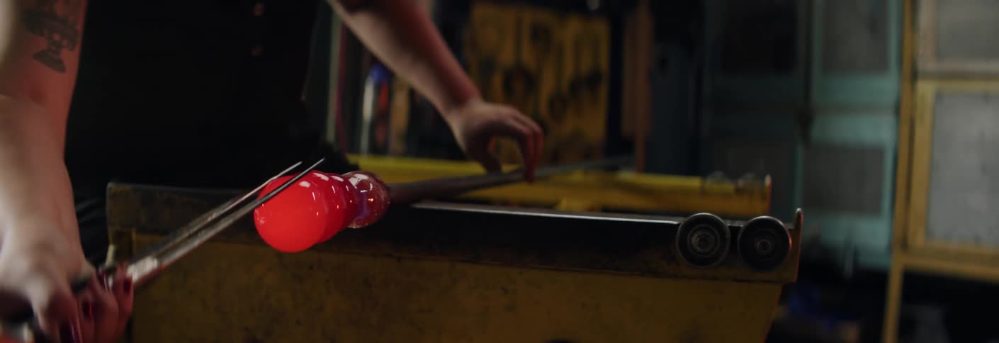 A workman shapes molten glass inside a workshop