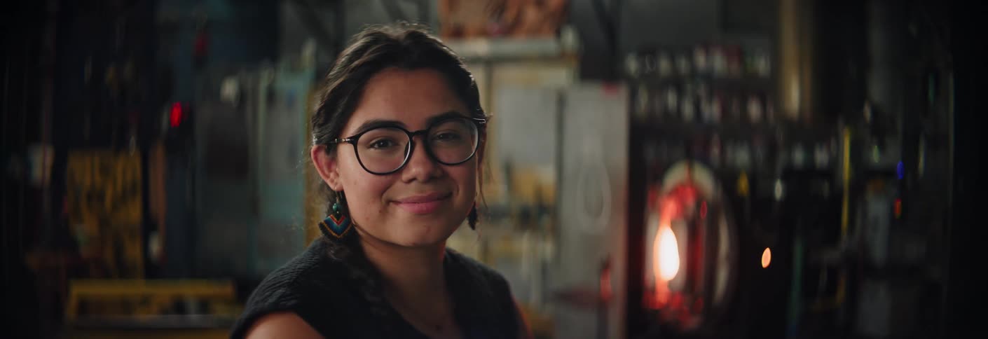 A woman smiles at the camera in an industrial workshop