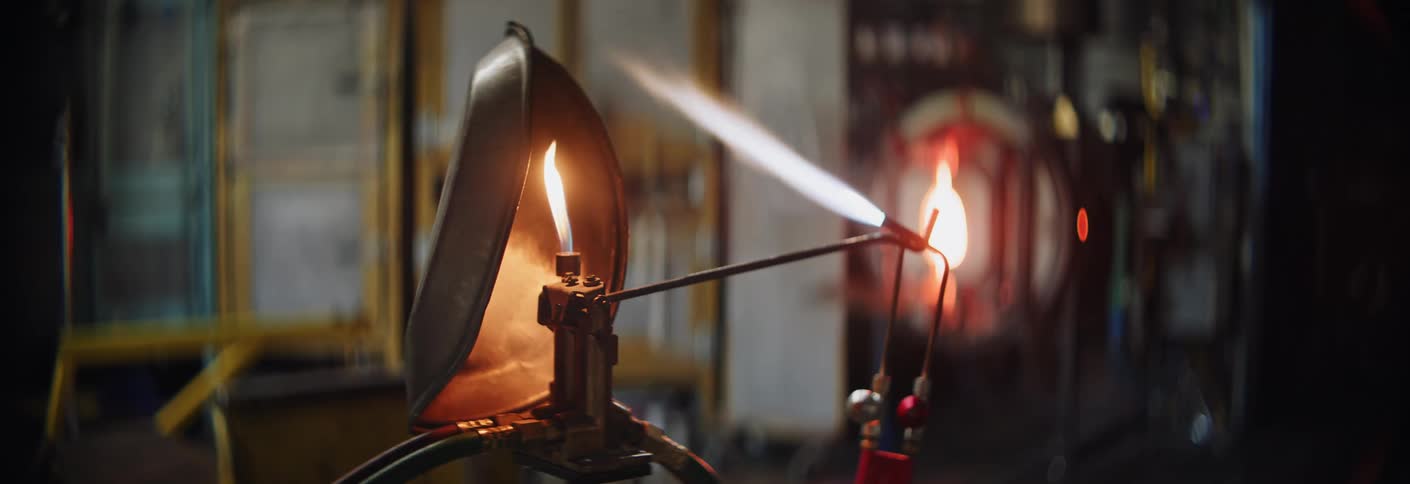 A torch is lit in a glass workshop
