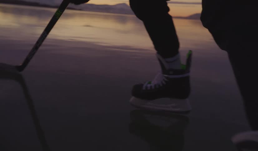 The hockey player moves the puck on the frozen lake