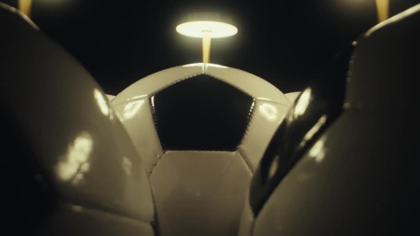 The lamp light is reflecting on the soccer balls in the dark room