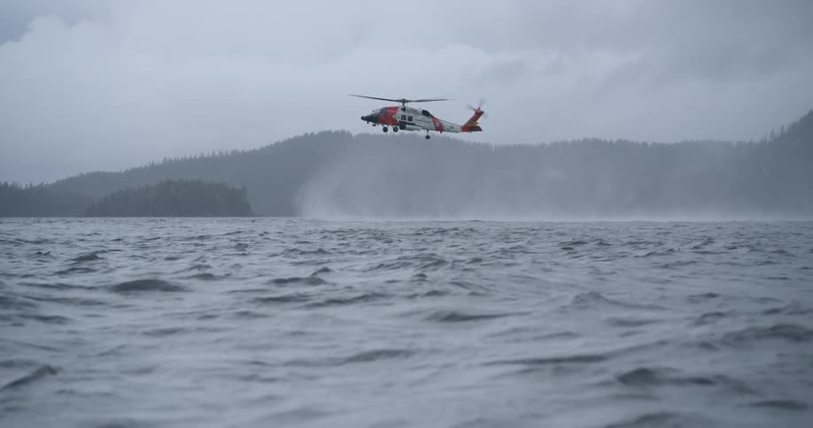 A helicopter hovers over the ocean on a cloudy day and the rotor wash pushes the water around in uneven waves