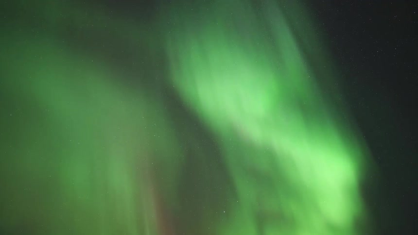 A mesmerizing timelapse captures brilliant green ribbons of the aurora borealis dancing and swirling gracefully across the vast starfilled night sky