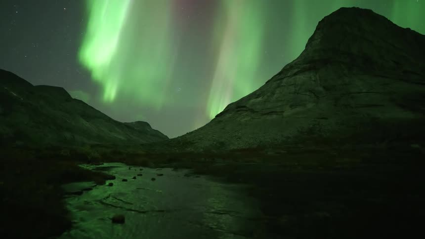 Green flares from an aurora flare over the dark mountain range