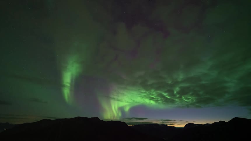 Mountains across the landscape as the northern lights illuminate the night sky