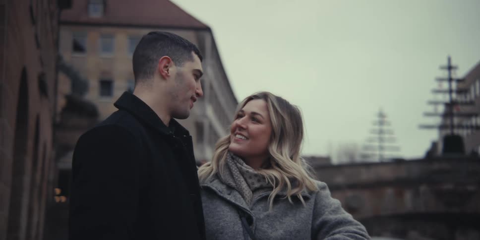 A smiling couple enjoys a relaxed conversation while standing on a city street