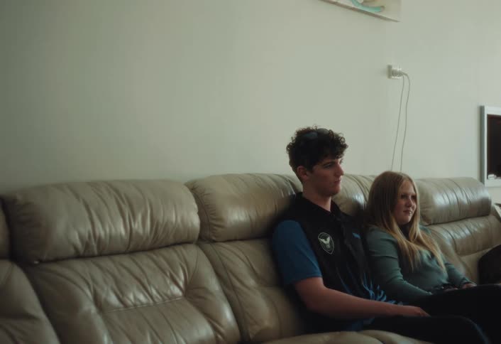 Two people sit side by side on a living room sofa