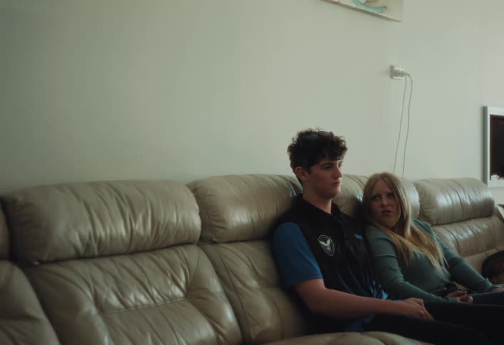 A young couple talks quietly together while sitting on a couch in the living room