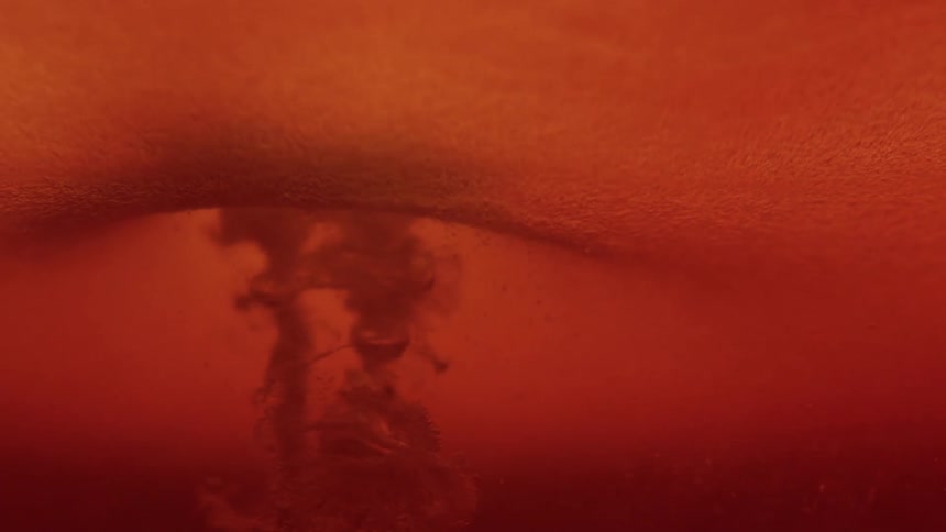 A close view shows a dark amber liquid with a thick layer of foam on top while bubbles and sediment swirl downward from the surface