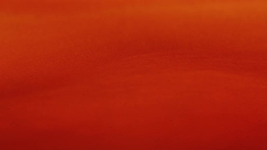 A macro view captures the rich slowmoving currents of a vibrant orange liquid as tiny bubbles gently drift through its viscous texture