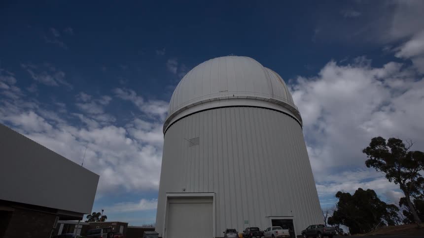 Astronomical observatory with a white dome under a blue sky with scattered clouds