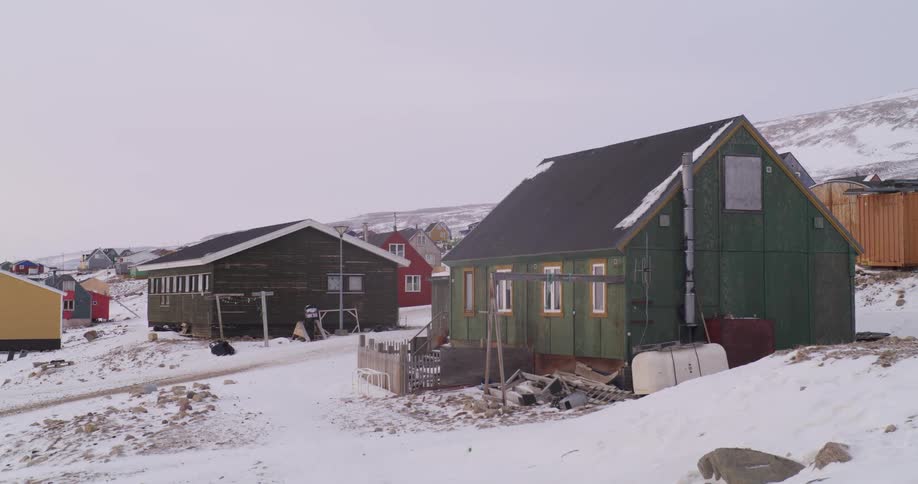 A person rides a four wheeler in a small arctic village