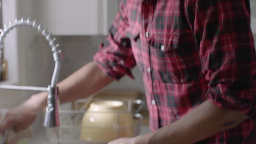 A person scrubs a pan in the kitchen